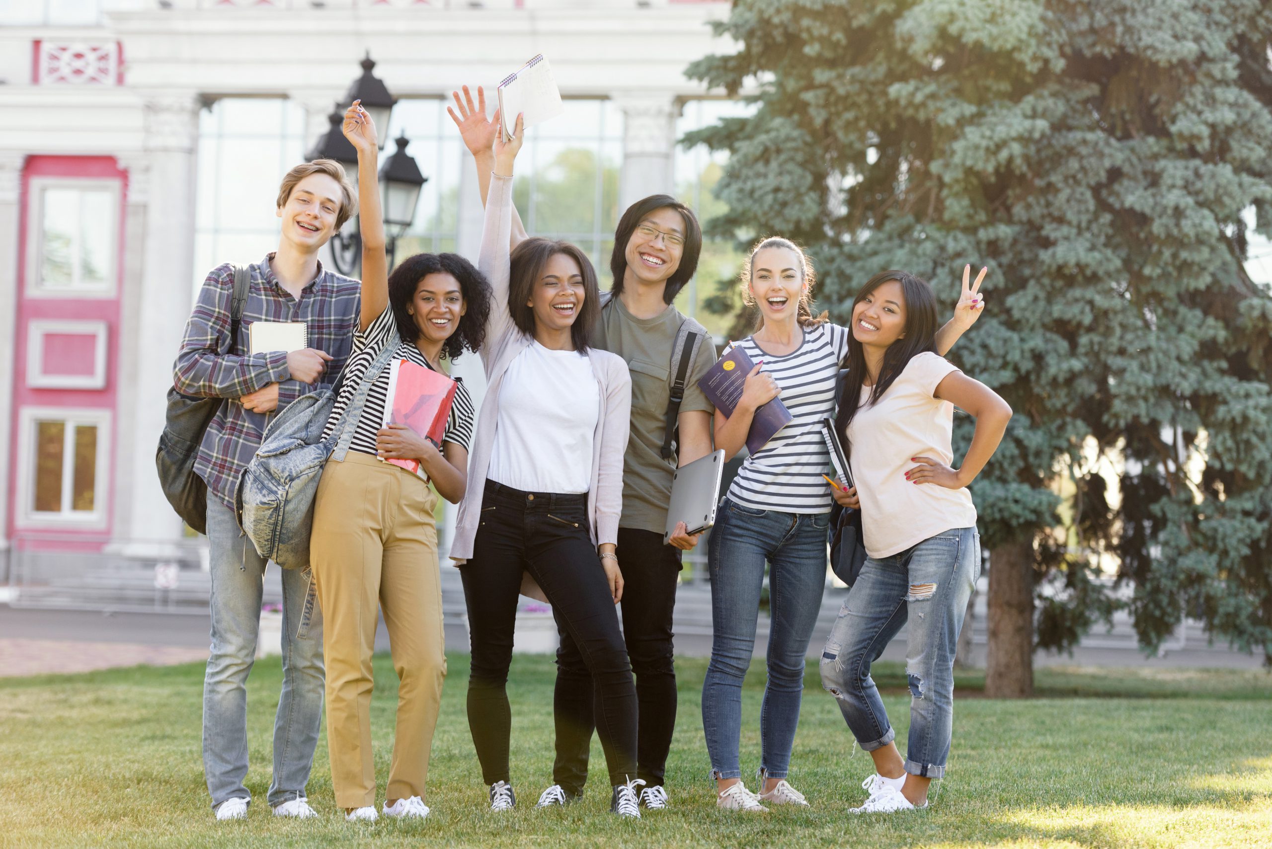 cheerful-students-standing-waving-outdoors
