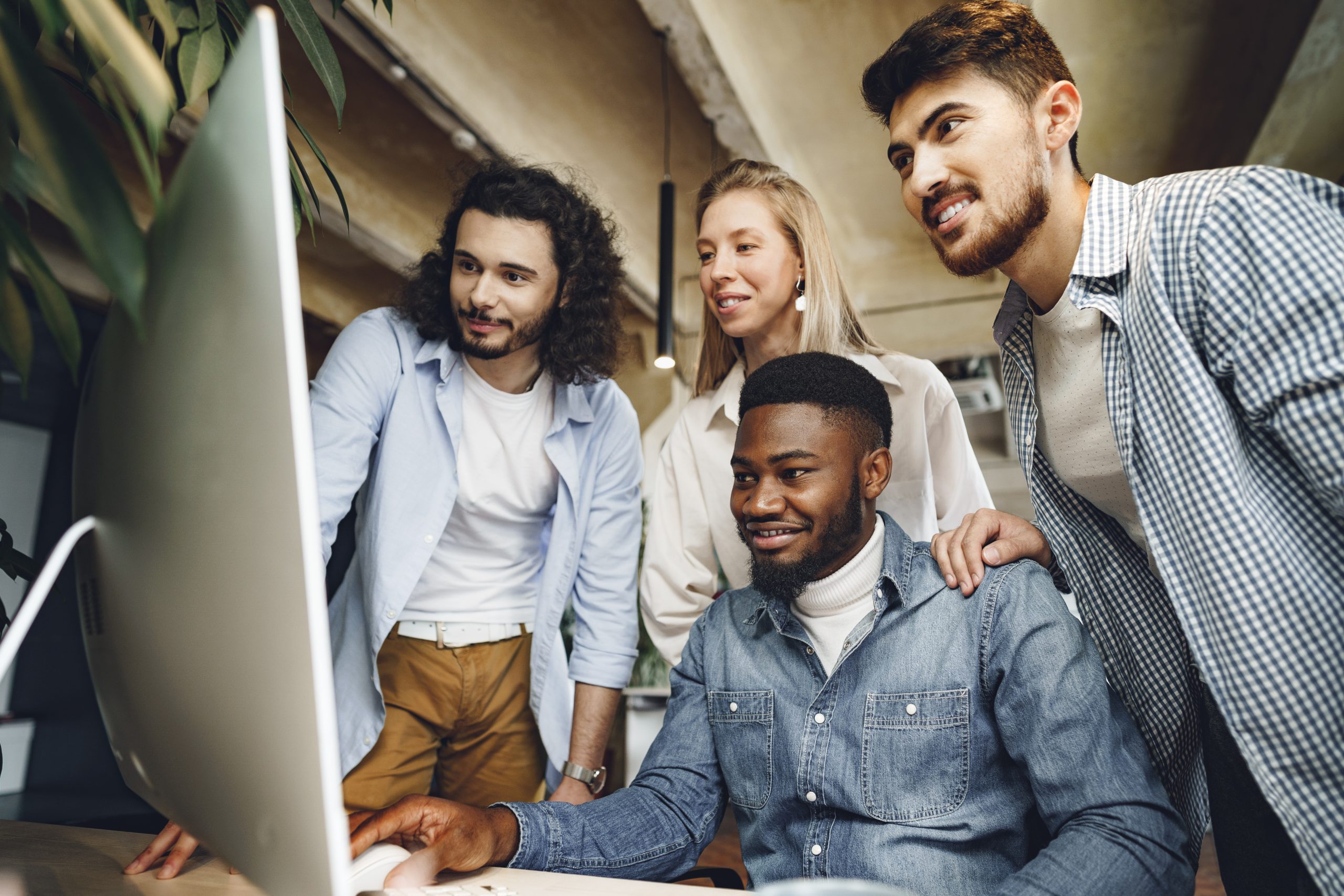 Four multi-ethnic colleagues looking computer screen looking